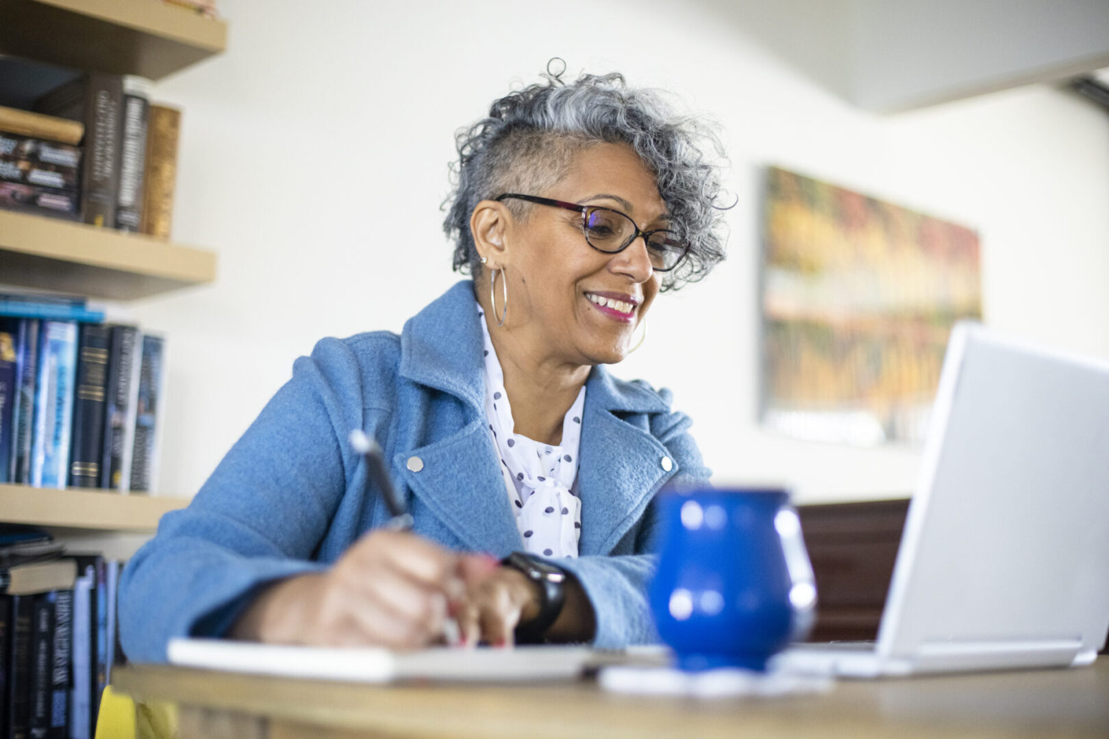 A beautiful mature black woman with gray hair working from home.